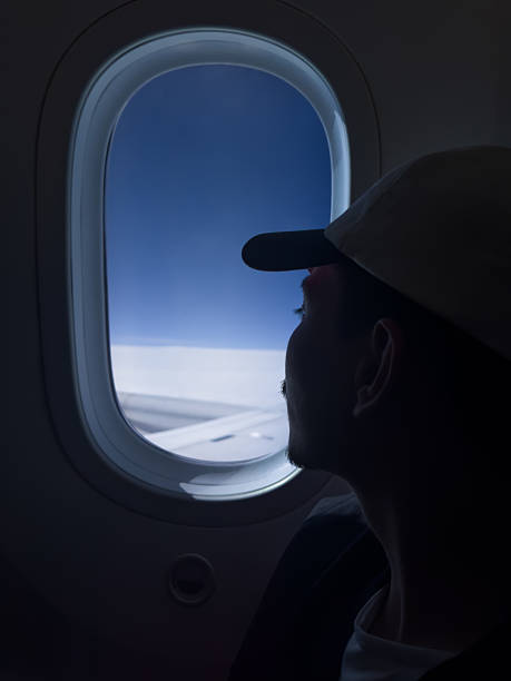 istock Young man looking out the airplane window contemplating the sky and clouds 2241663147