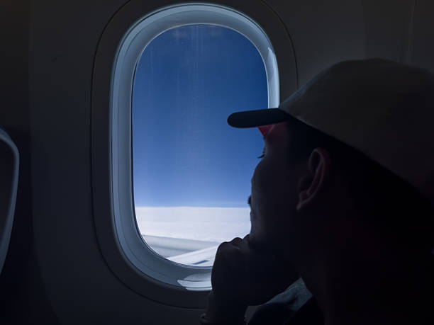 istock Young man observing the aerial landscape through the airplane window 2241663154
