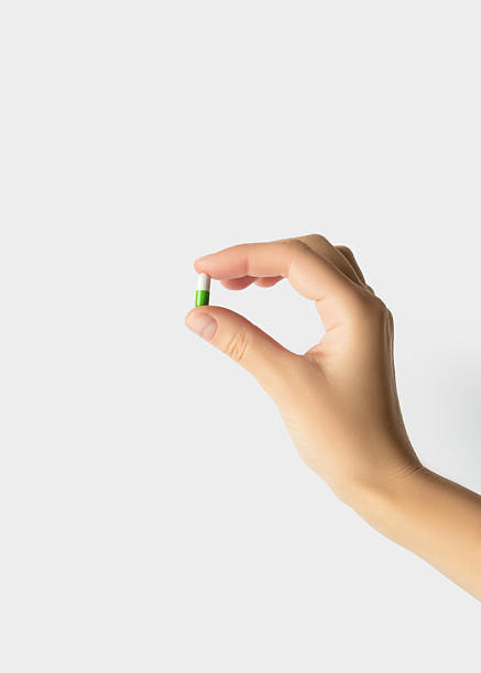 istock Hand Holding a Green and White Medicine  Capsule Isolated On White Background 2241663263