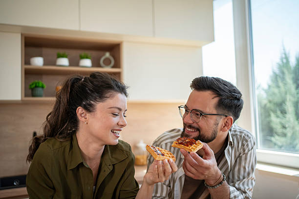 istock Happy couple enjoying breakfast waffles and laughing in kitchen 2241664363