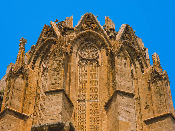 Editorial photo taken on 13 June 2025 in Famagusta, Cyprus, showing the detailed Gothic facade of the Saint Nicholas Cathedral, now known as Lala Mustafa Pasha Mosque. The pointed arches, tracery, and intricate stone carvings of the medieval structure stand out against a vivid blue sky.