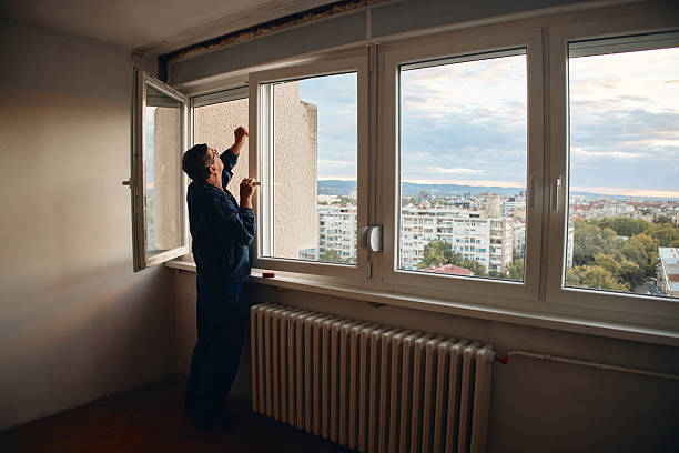 istock Blue Collar Worker Installing Window in Urban Apartment Setting with City View 2241667695
