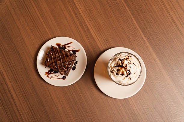 Top view of a coffee milkshake with a brownie served on different plates.