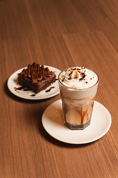 A coffee milkshake with a brownie on a wooden table.