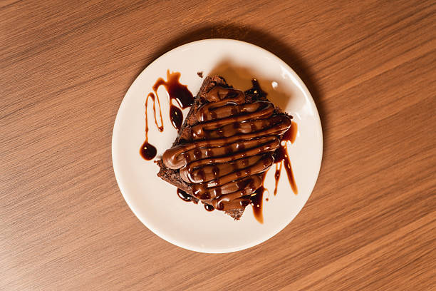 Top view of a brownie served on a plate, on a wooden table.