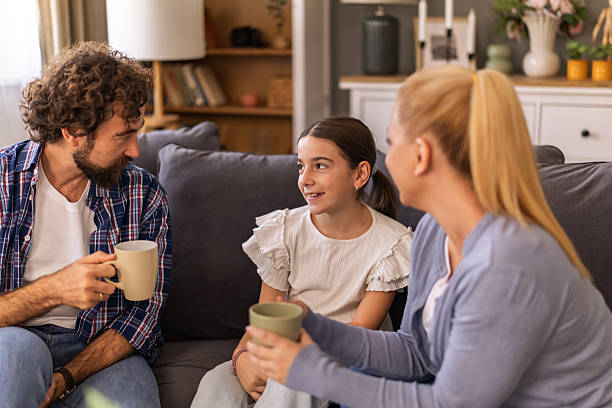 istock Happy parents talking to their daughter while drinking coffee and sitting on sofa in the living room 2241678584
