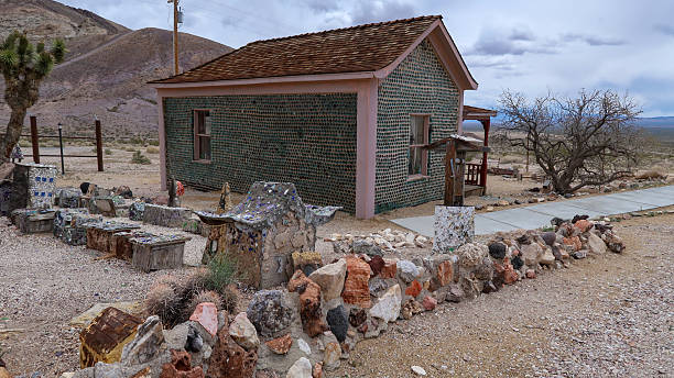 The famous Bottle House in Rhyolite, Nevada, constructed in 1906 using thousands of glass bottles and adobe mortar, stands as one of the most iconic structures in this desert ghost town. Surrounded by desert landscape and distant mountains, the Bottle House represents early recycling ingenuity and the rich mining heritage of southern Nevada’s early 20th-century boomtown era.