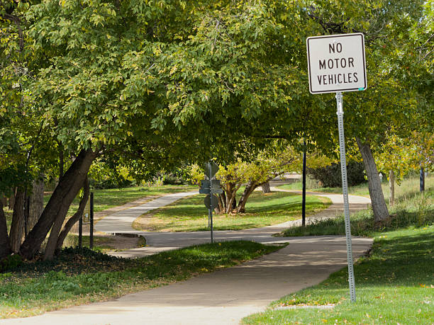 Sign prohibiting motor vehicles along a winding paved path in a green park