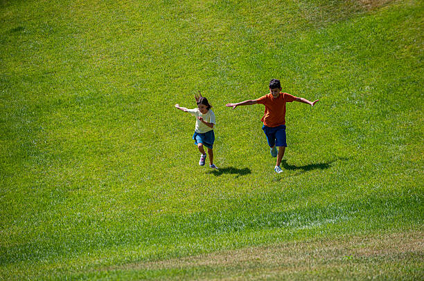 A helping hand. Caring little daughter helps her father do  somersault forward rolls in flower meadow. Family fun and sharing moments outdoors in spring nature.