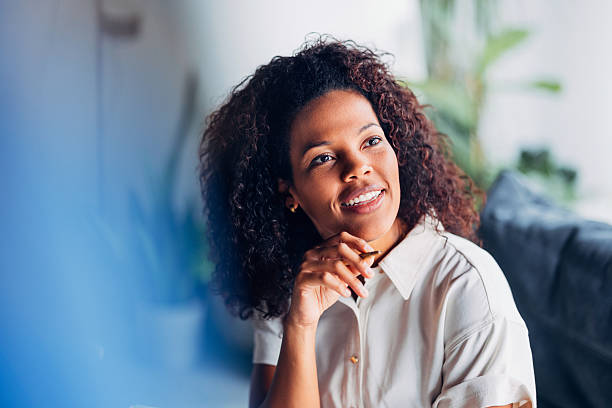 istock Thoughtful Woman Sitting Indoors with Natural Light and Cheerful Expression 2241691477