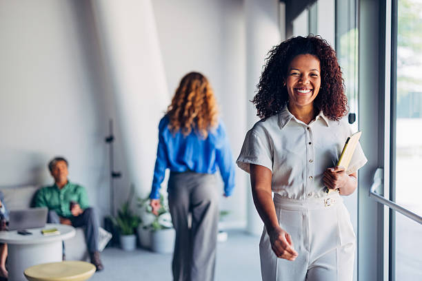 istock Smiling Woman Walking Indoors in a Bright Office Environment 2241691503