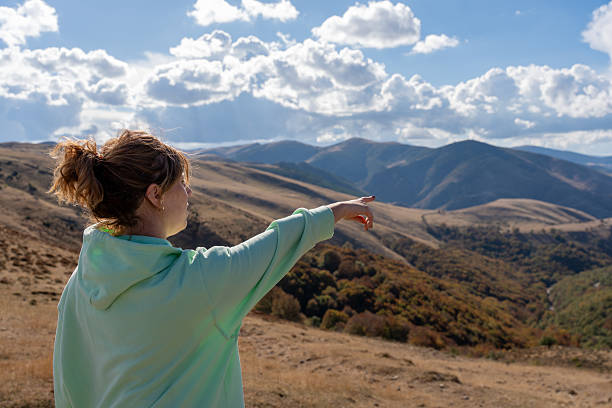 istock Woman hiking in mountains pointing forward to horizon 2241692418