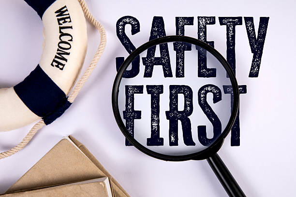 Magnifying Glass Focusing on Text Safety First with Lifebuoy Symbol Representing Caution and Workplace Protection Concept.