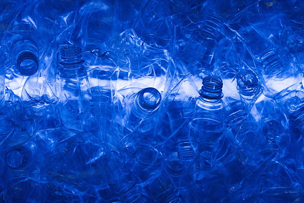 A row of neatly arranged plastic bottles stands against a vibrant green backdrop, ready for recycling.
