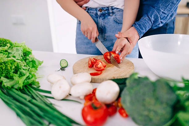 istock a man hugs a girl while she cuts a tomato on a salad. 2241709198