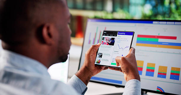 istock Black American Man Trading Stocks On Foldable Phone 2241714733
