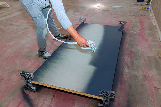istock Worker spraying paint on large wooden surface in an indoor workspace during work day 2241719893