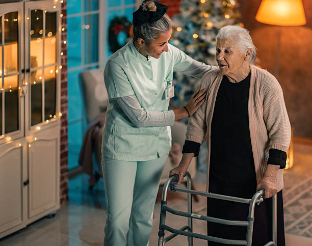 istock Caregiver helping elderly woman walkwith a walker during Christmas evening 2241733549