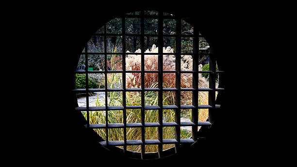 istock Round lattice window frame with garden view through traditional Japanese architecture, autumn foliage background 2241737262