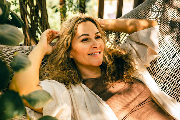 istock Relaxed woman lying on a hammock in sunlight surrounded by greenery enjoying a slow summer day 2241738120