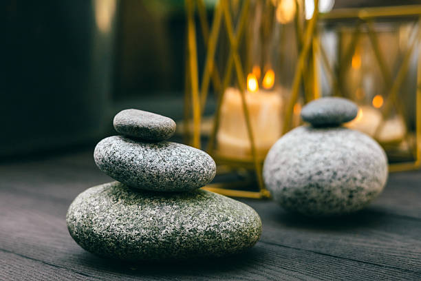 istock Stacked zen stones with burning candles in soft warm light on wooden surface 2241738384