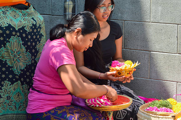 istock Mother focused on ceremonial canang while daughter holds finished craft 2241742927