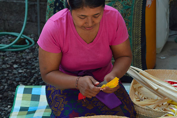 istock High angle view of Balinese mother shaping yellow palm leaf patterns 2241747257