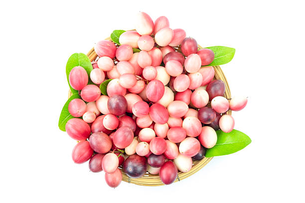 Group of fresh ripe Bengal-currants, Carandas-plum , Karanda with green leaves in a wooden basket isolated on white background top view flat lay stack
