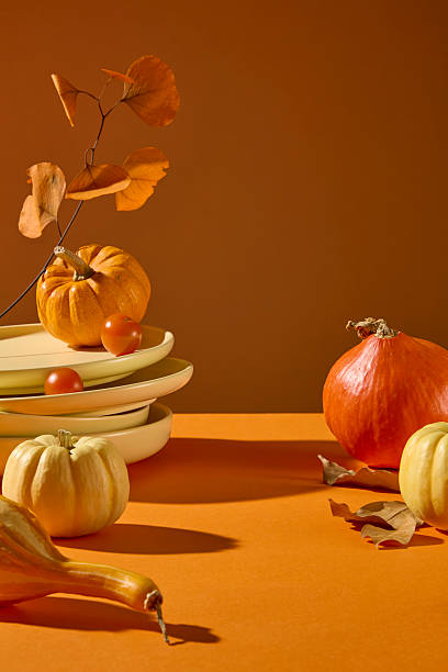 istock Dynamic composition of falling autumn leaves with pumpkins and stacked tableware. Perfect for festive fall design, banner, or seasonal campaign visuals. 2241750730