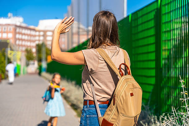 istock Mother waving goodbye to daughter going to school 2241750978