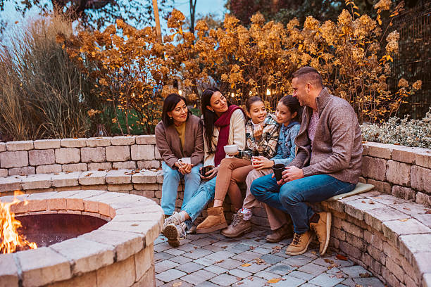 istock Family sitting by fire pit during cold autumn evening. 2241751191
