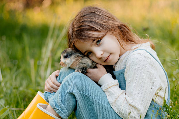 istock Young girl with pet rabbit sitting on grass. 2241751494