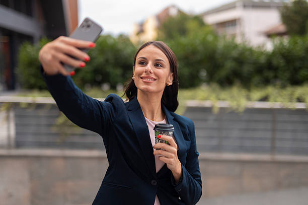 istock Smiling businesswoman taking a selfie outdoors while holding coffee cup. 2241761961