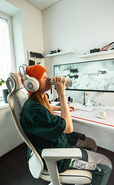 istock Professional gaming desk setup with high-end peripherals, sleek monitor, and organized workspace. Gamer, wearing a headset, focuses on game strategy while staying hydrated with an energy drink. 2241762077