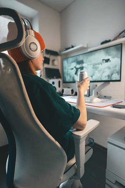 istock Focused gamer in white gaming workspace reaching for energy drink while playing fast-paced online game. Keyboard and high-resolution monitor create immersive digital experience in competitive gaming. 2241762129