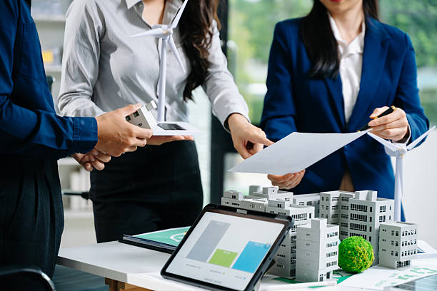 istock Professionals presenting wind turbine and building models during a meeting. Ideal for green energy, smart city planning, 2241763307