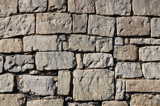 istock background, stone wall structure, constructed from light-colored stones of varying sizes, with some stones featuring darker veins or inclusions 2241764390