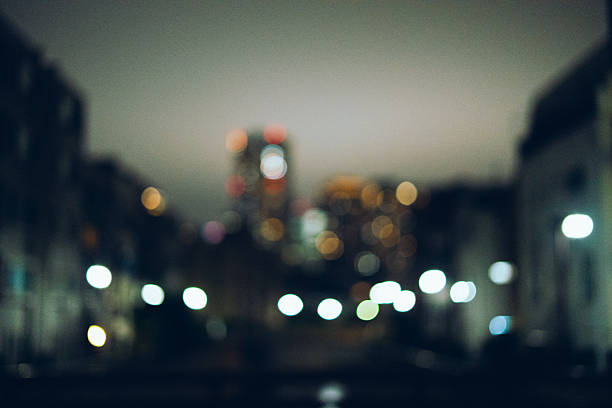 A dreamy urban nightscape captured out of focus, showing glowing orbs of city lights.The soft bokeh creates a serene and atmospheric mood, evoking a sense of quiet reflection in the middle of the city.