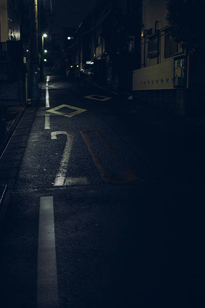 istock Quiet Wet Street at Night with Speed Limit Markings 2241764550