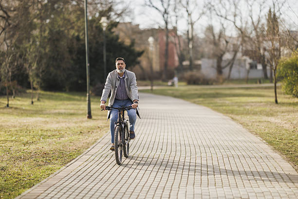 istock Man Riding Bike Down Brick Road In the Park 2241769740