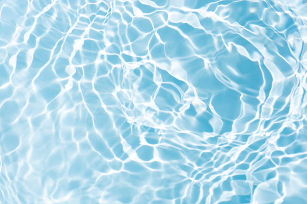 istock Blue water with ripples on the surface. Defocus blurred transparent blue colored clear calm water surface texture with splashes and bubbles. Water waves with shining pattern texture background. 2241776451