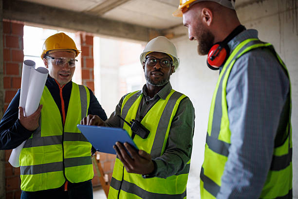istock Team of professionals at a construction site examining project blueprints 2241780328