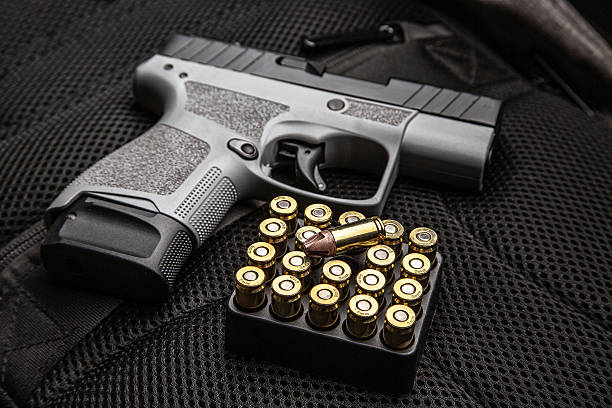 istock A compact two-tone pistol and ammunition on a dark tactical gear background. 2241783751