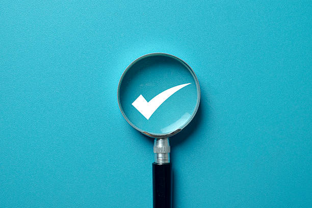 istock Magnifying glass focusing on a white checkmark or tick icon on a blue background. 2241784987
