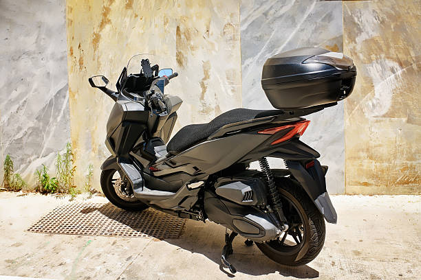 istock Modern Black Scooter with Top Case Parked Near Textured Wall 2241788590