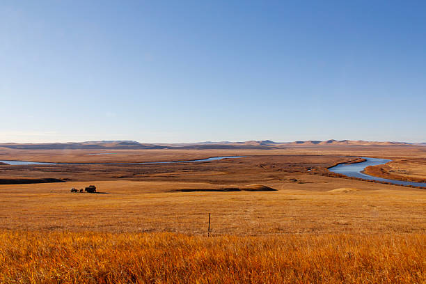 istock Vast open grassland with winding river under clear sky 2241791133