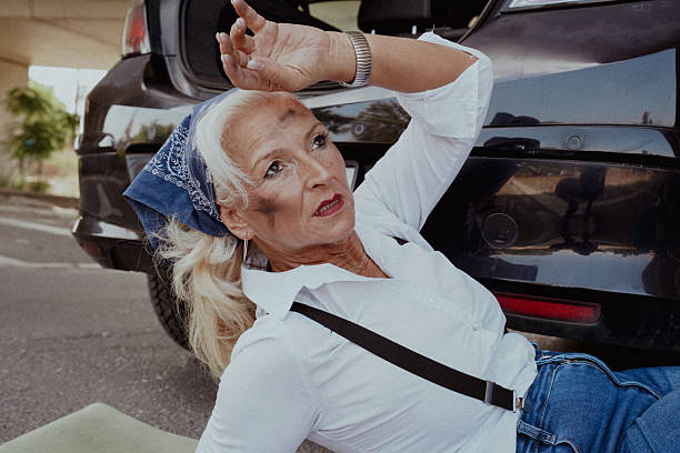 A middle-aged woman dressed casually is lying under a car, confidently performing repair work with a smile on her face. Holding tools and appearing fully self-reliant, she breaks gender stereotypes while enjoying a task traditionally dominated by men. This photo series celebrates female empowerment, independence, technical skills, and women embracing non-traditional roles or hobbies.