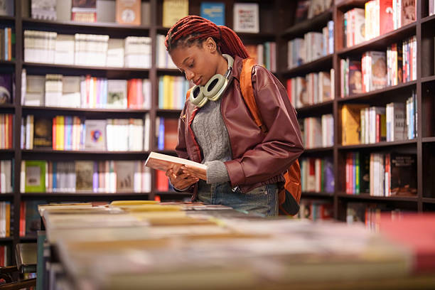 istock Woman reading a book in a bookstore aisle 2241799358