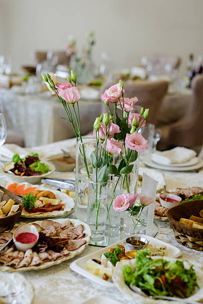 istock A beautifully set banquet table featuring a fresh, delicate centerpiece of pink Eustoma flowers surrounded by a generous spread of European-style appetizers, including sliced meats, salads and cheese 2241803893