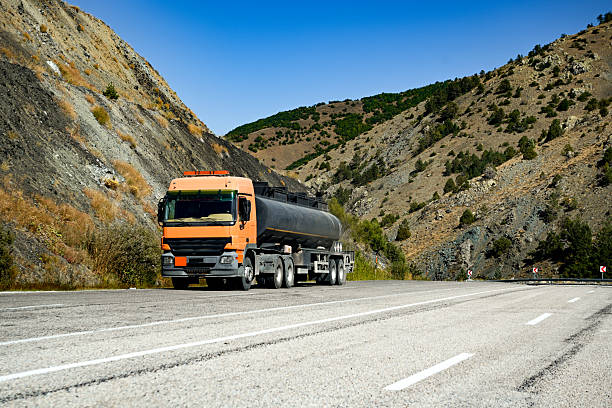 sewage tank on a truck driving on the road behind few cars and a trailer